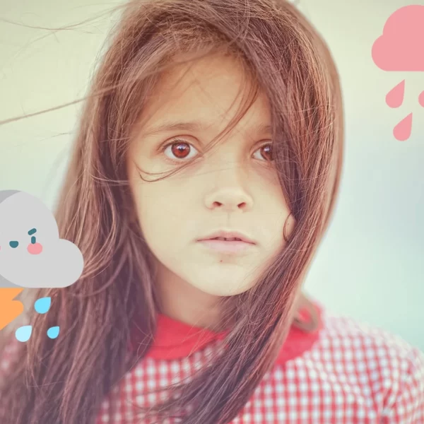 Una niña pequeña está parada frente a una nube y la lluvia, mostrando síntomas de Trastornos de ansiedad en niños.