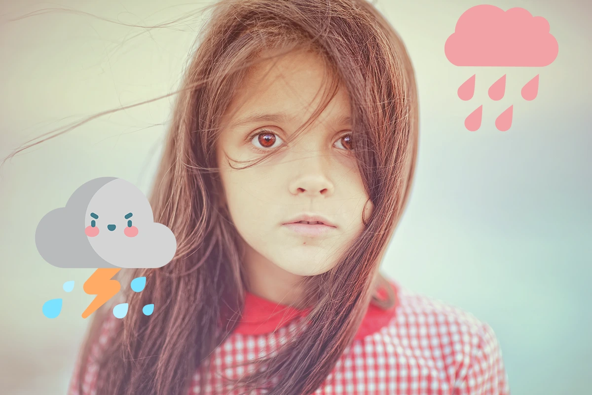 Una niña pequeña está parada frente a una nube y la lluvia, mostrando síntomas de Trastornos de ansiedad en niños.