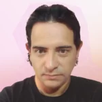 Un hombre con una camisa negra con fondo rosa.