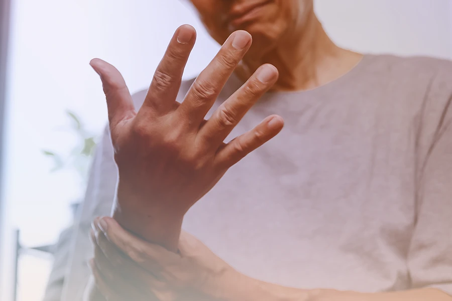 Persona sosteniendo su brazo, posiblemente experimentando hormigueo y dolor en el área de la muñeca.