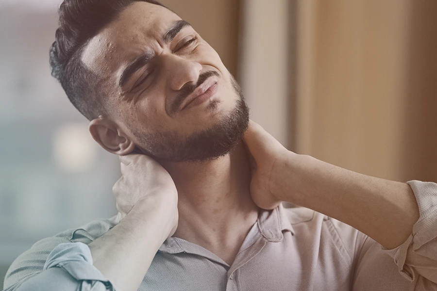 Un hombre que experimenta dolores musculares por ansiedad y malestar en el cuello.