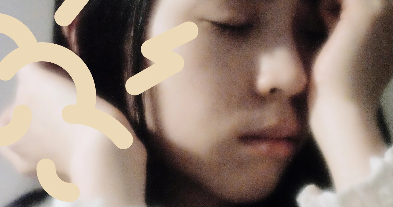 Primer plano de una persona con los ojos cerrados, apoyando la mejilla en la mano. Formas abstractas de color beige se superponen a la imagen, reflejando sutilmente el efecto calmante sobre el estrés fisiológico.